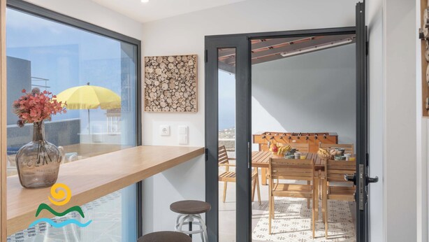 A modern kitchen with a large window, a wooden countertop, and a vase with flowers. - Calheta beautiful character cottage | Villa Loreto (Arco Da Calheta)