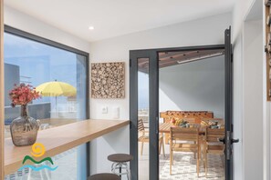 A modern kitchen with a large window, a wooden countertop, and a vase with flowers.