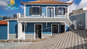 A two-story building with a blue facade, a tiled roof, and a staircase leading to the upper floor. - Calheta beautiful character cottage | Villa Loreto (Arco Da Calheta)