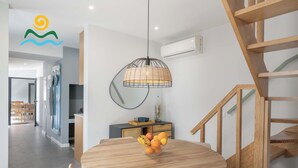 A modern dining area with a round wooden table, a wicker pendant light, and a fruit bowl. - Calheta beautiful character cottage | Villa Loreto (Arco Da Calheta)