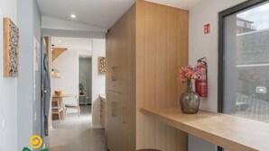 A modern kitchen with wooden cabinets, a bar counter, and a fire extinguisher on the wall. - Calheta beautiful character cottage | Villa Loreto (Arco Da Calheta)