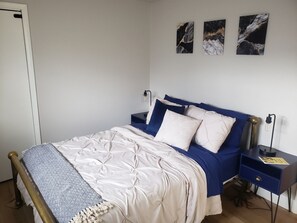 Un dormitorio con una cama, mesitas de noche y tres obras de arte colgadas en la pared.