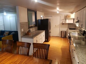Cocina compacta con refrigerador, estufa y pileta. Hay un comedor con mesa y sillas.