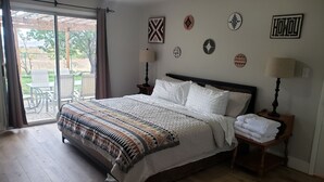 Ein Schlafzimmer mit einem großen Bett, Holzboden, einer Schiebetür zu einem Außenbereich und mehreren Wanddekorationen.