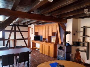 A rustic kitchen with wooden cabinets, a stove, and a dining area with a table and chairs. - Le Dorli Schopf Gîte (Dorlisheim)