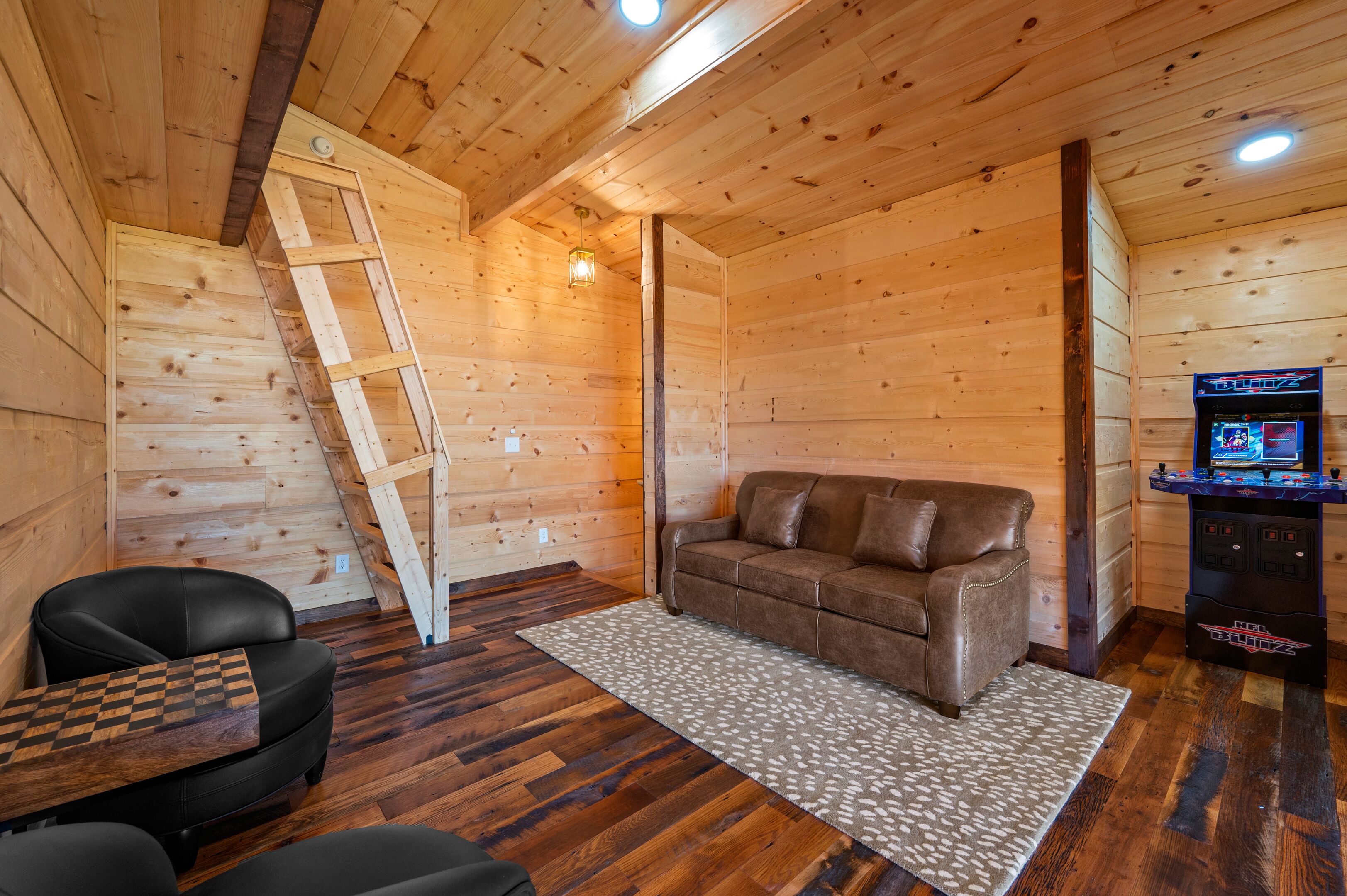 A cozy cabin interior with a wooden interior, a sofa, a small table, and a video game console.