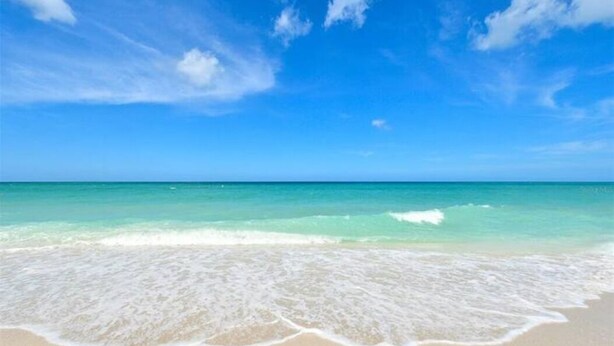 Una playa con agua azul cristalina y una orilla arenosa.