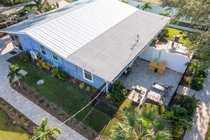 Ein blaues Haus mit flachem Dach, einer Terrasse mit Gartenmöbeln und einem kleinen Garten.