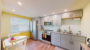 Una cocina compacta equipada con refrigerador, microondas, estufa y pileta.