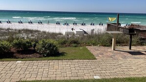 A beach with rows of sun loungers and a wooden deck with a trash bin. - SPECTACULAR FIRST FLOOR “BEACHFRONT”
CONDO COMPLETELY RENOVATED ON CRYSTAL BEACH (Destin)