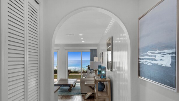A hallway with a view of the ocean, a dining area with a table and chairs, and a large framed artwork on the wall. - SPECTACULAR FIRST FLOOR “BEACHFRONT”
CONDO COMPLETELY RENOVATED ON CRYSTAL BEACH (Destin)
