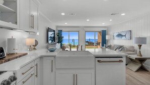 A modern kitchen with white cabinetry, a central island, and a view to the outside. - SPECTACULAR FIRST FLOOR “BEACHFRONT”
CONDO COMPLETELY RENOVATED ON CRYSTAL BEACH (Destin)