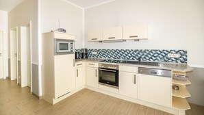 A modern kitchen with white cabinets, a microwave, oven, and a coffee maker. - Amselresidenz 2 - DROSSEL (Binz)