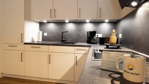 A modern kitchen with white cabinets, a black countertop, and a coffee machine.
