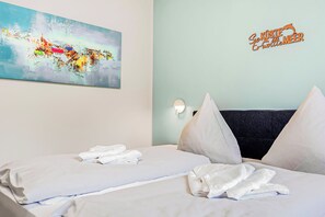 Une chambre d’hôtel avec un lit, des oreillers, un tableau et un panneau accroché au mur.