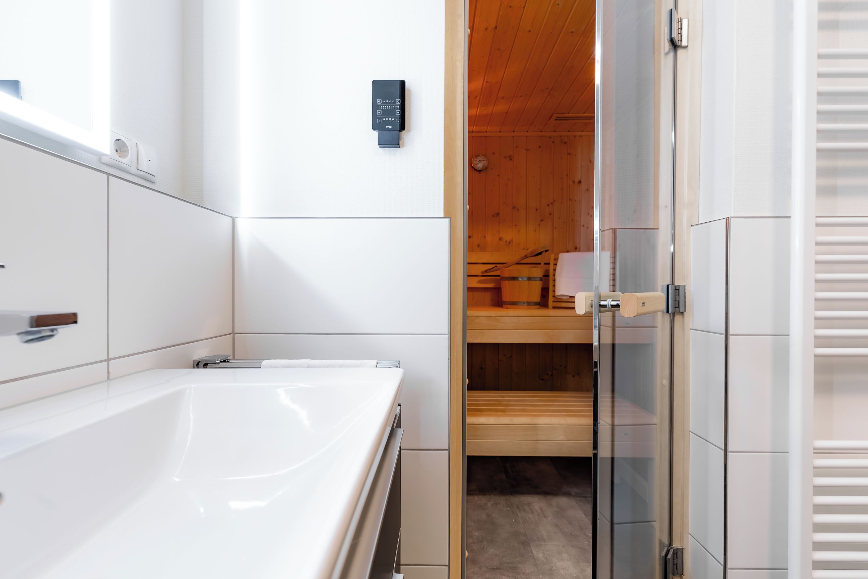 Une salle de bain moderne avec une baignoire, un sauna en bois et une cabine de douche en verre.