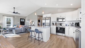 A modern kitchen with white cabinets, stainless steel appliances, and a central island with bar stools.