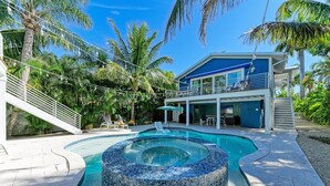 A modern house with a pool, a covered patio, and a staircase leading to a balcony. - Blue Hideaway- 5 bedroom with Separate Guest House, Private Pool/Spa! (Anna Maria)