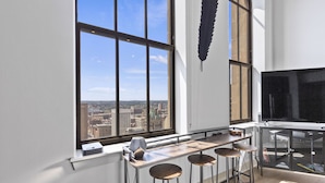Una cocina moderna con un ventanal grande, una barra con taburetes y vistas a la ciudad.
