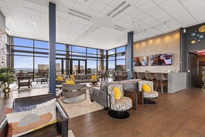 A spacious lobby with a high ceiling, large windows, and a modern seating area with sofas and chairs. - Distinguished Apartment Rooftop Deck (Baltimore)