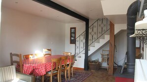Un comedor con una mesa dispuesta para cuatro, una escalera y un estufa de leña.