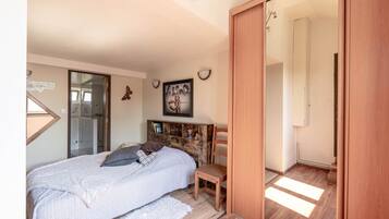 Een slaapkamer met een bed, een stoel, een kledingkast en een spiegel.
