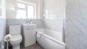 Une salle de bain moderne équipée de toilettes, d’un lavabo et d’une baignoire.