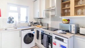 Una cocina moderna con armarios blancos, lavadora integrada, microondas y tostadora.