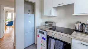 A compact kitchen with a dishwasher, a stove, and a kettle. - Beautiful Sea View 2 bedroom Sleeps 6-Free Parking (Bournemouth)