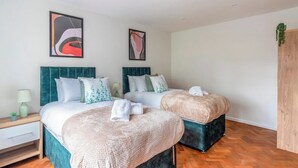 Un dormitorio moderno con dos camas, una mesita de noche y un armario de madera.