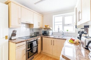 Een koelkast, een oven, een broodrooster, kookgerei, borden en bestek