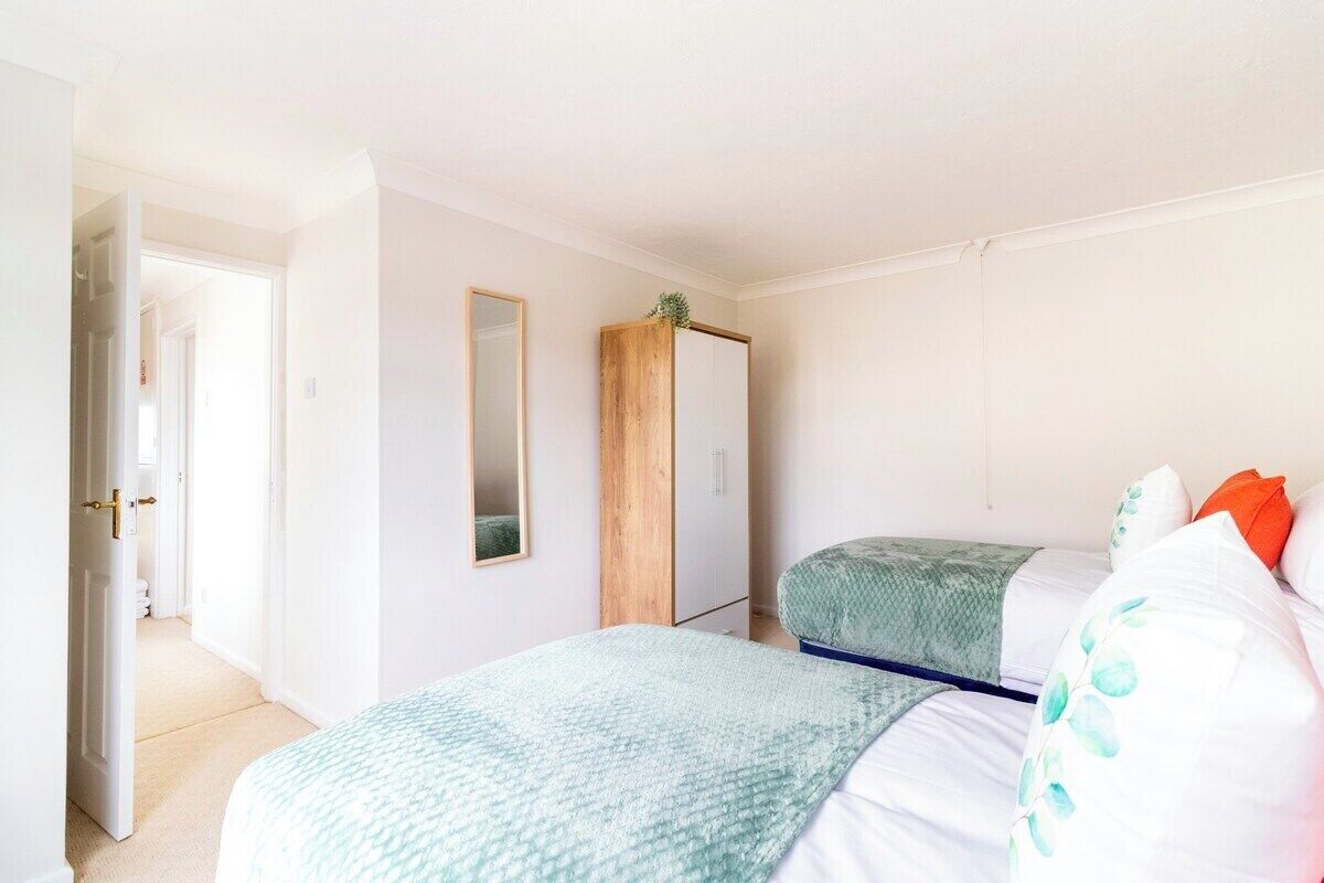 A bedroom with two beds, a wardrobe, and a mirror.