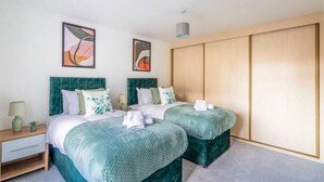 A hotel room with two beds, a nightstand, a lamp, and artwork on the walls. - Large Sea View 2 bedroom Sleeps 6 - Free Parking (Bournemouth)
