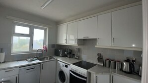 Une cuisine moderne avec des meubles blancs, un lave-linge encastré, un évier et une cuisinière.