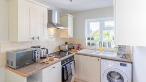 A compact kitchen with a toaster, kettle, oven, and washing machine. - Panoramic Sea View Apartment Sleeps 4-Free Parking (Bournemouth)