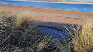 Une plage avec un ciel dégagé et des collines qui se dessinent à l’horizon.