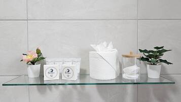 A bathroom shelf with toiletries, a tissue box, and two potted plants.