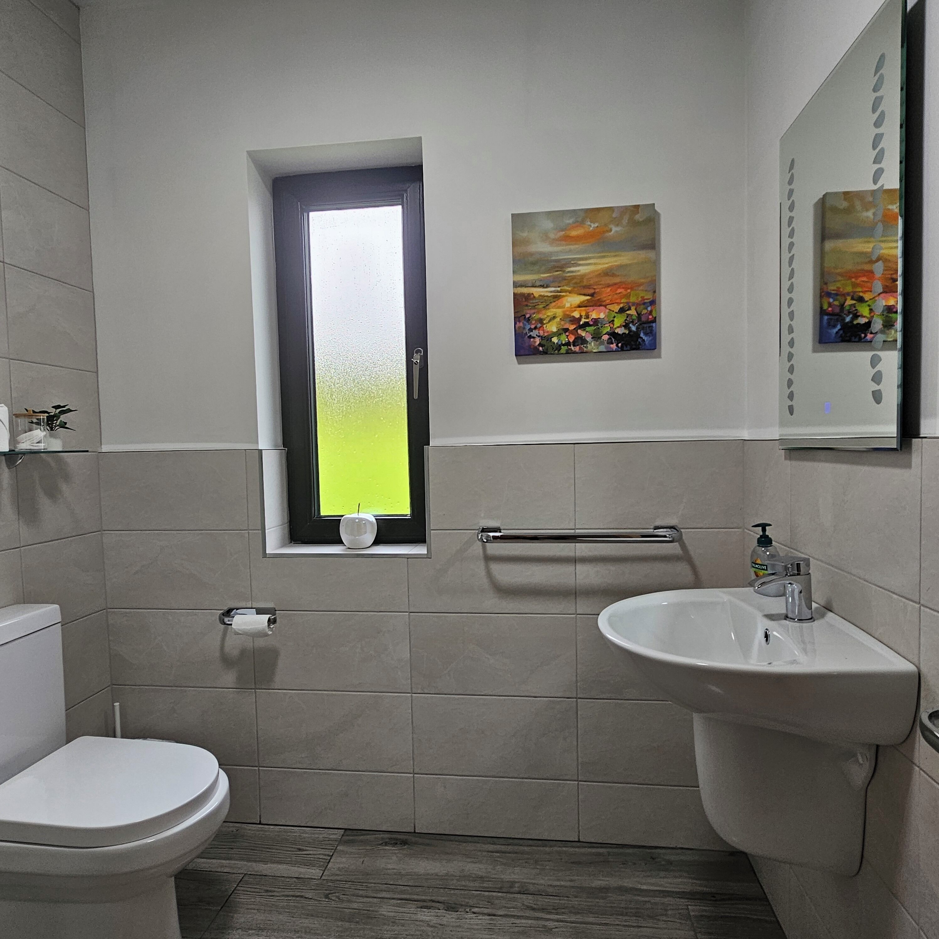 A bathroom with a toilet, sink, and window.