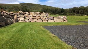 A stone wall, a grassy area, and a hill in the background.