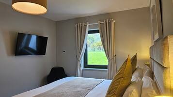 A hotel room with a bed, a TV mounted on the wall, a window with curtains, and a ceiling light.