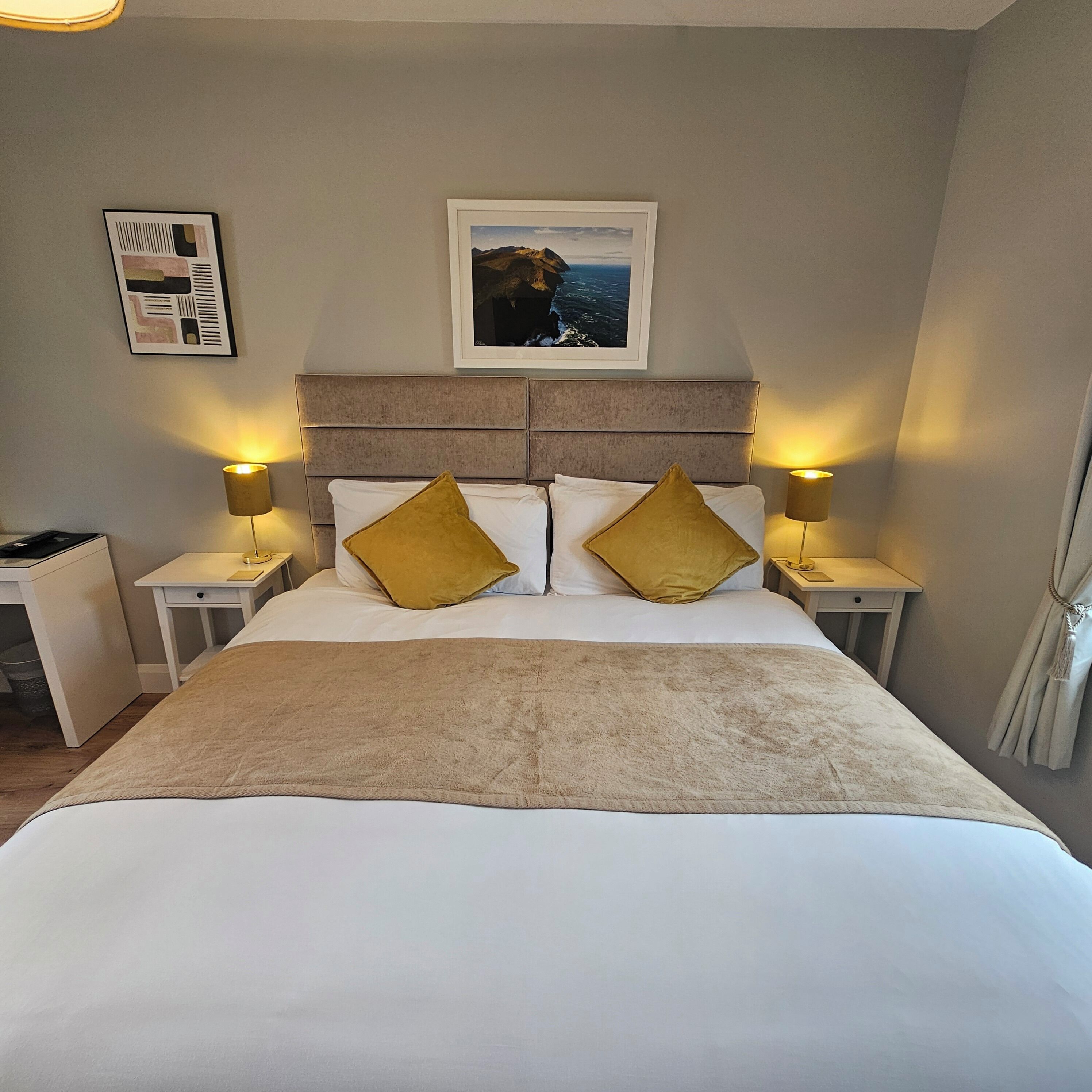 A neatly made bed with two pillows, a headboard, and two bedside lamps.