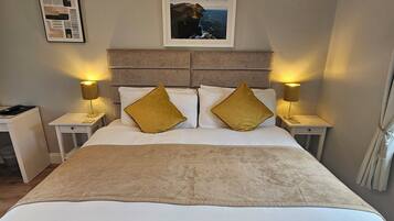 A neatly made bed with two pillows, a headboard, and two bedside lamps.