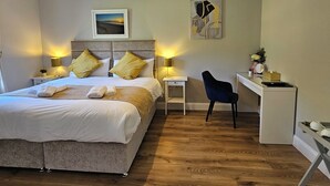 A modern hotel room with a large bed, bedside lamps, a desk, and a chair.