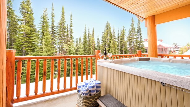 Ein Holzbalkon mit Whirlpool, Handtüchern und einer Weinflasche.