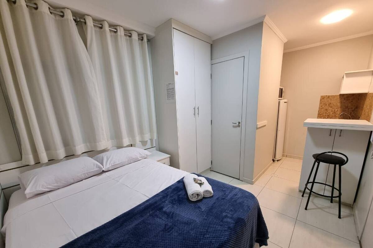 A hotel room with a bed, a desk, a chair, and a wardrobe.