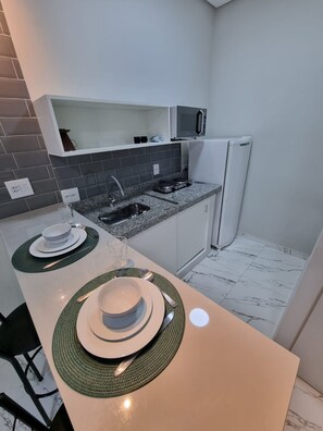Eine kleine Küche mit Mikrowelle, Kühlschrank und Arbeitsplatte aus Granit.