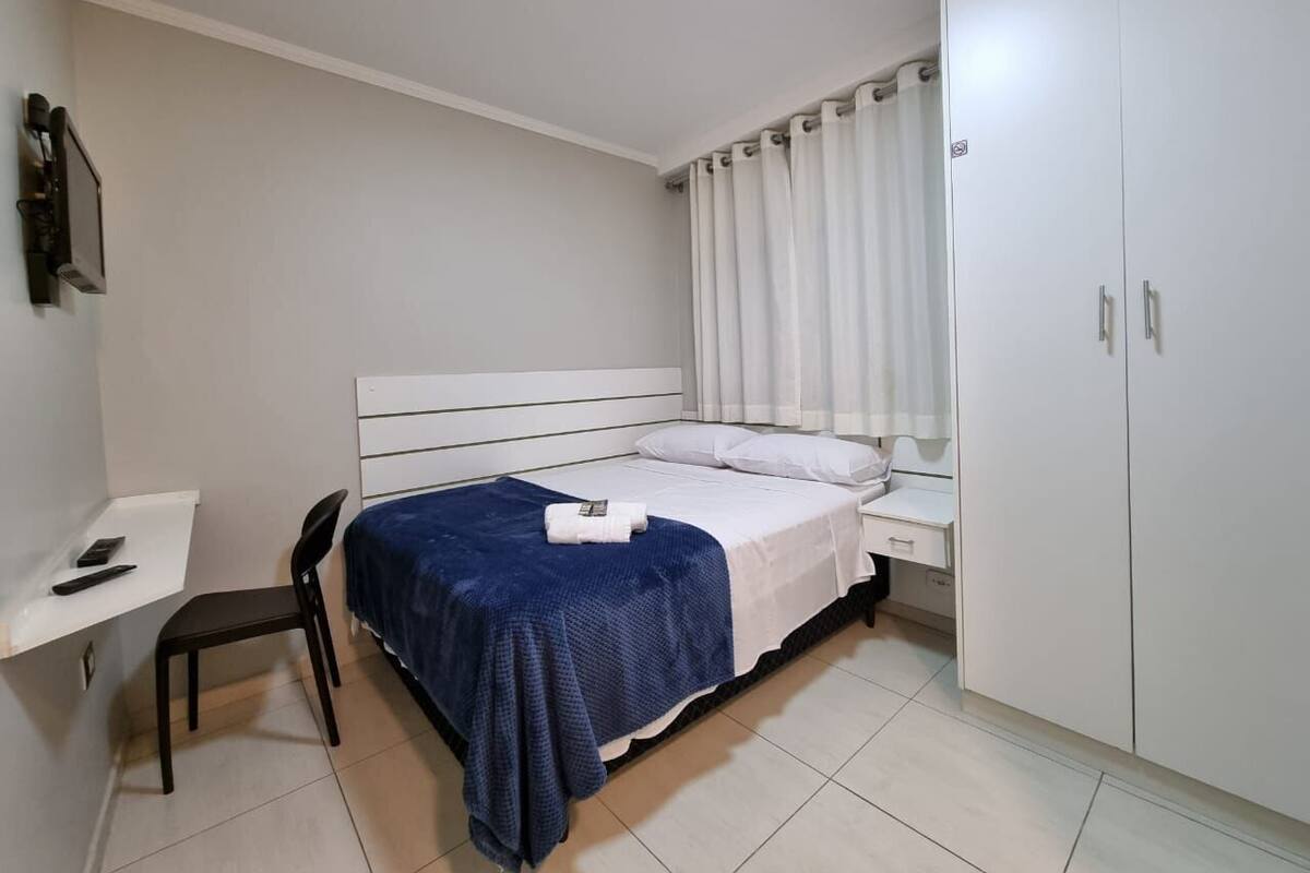 A bedroom with a bed, a desk, a chair, and a wardrobe.