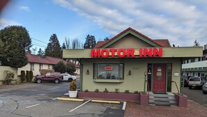 Un Motor Inn con un letrero rojo, un estacionamiento y una puerta roja.