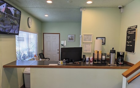 A reception desk with a computer, coffee maker, and framed certificates.