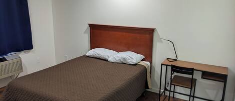 Un dormitorio con cama, escritorio y silla.
